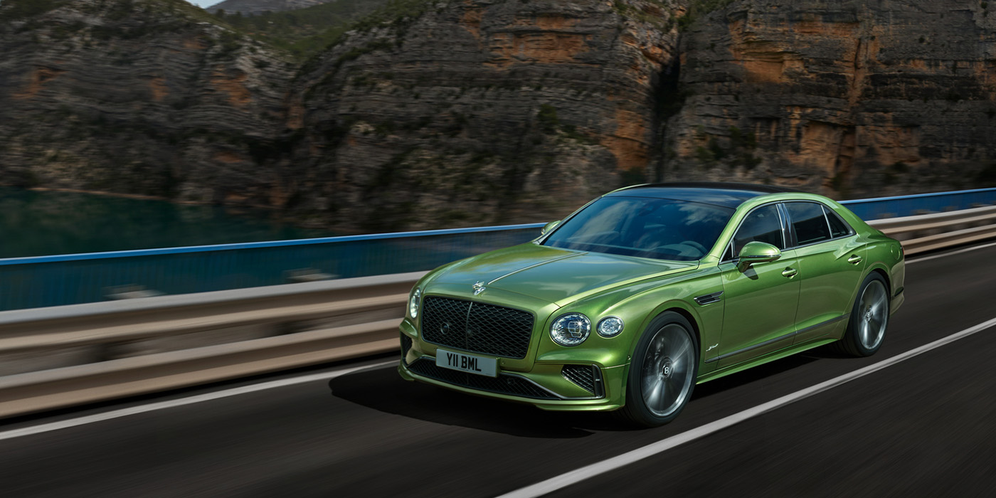 Bentley Roma Bentley New Flying Spur Speed v8 hybrid sedan driving dynamically on a mountain road in Tourmaline Green paint
