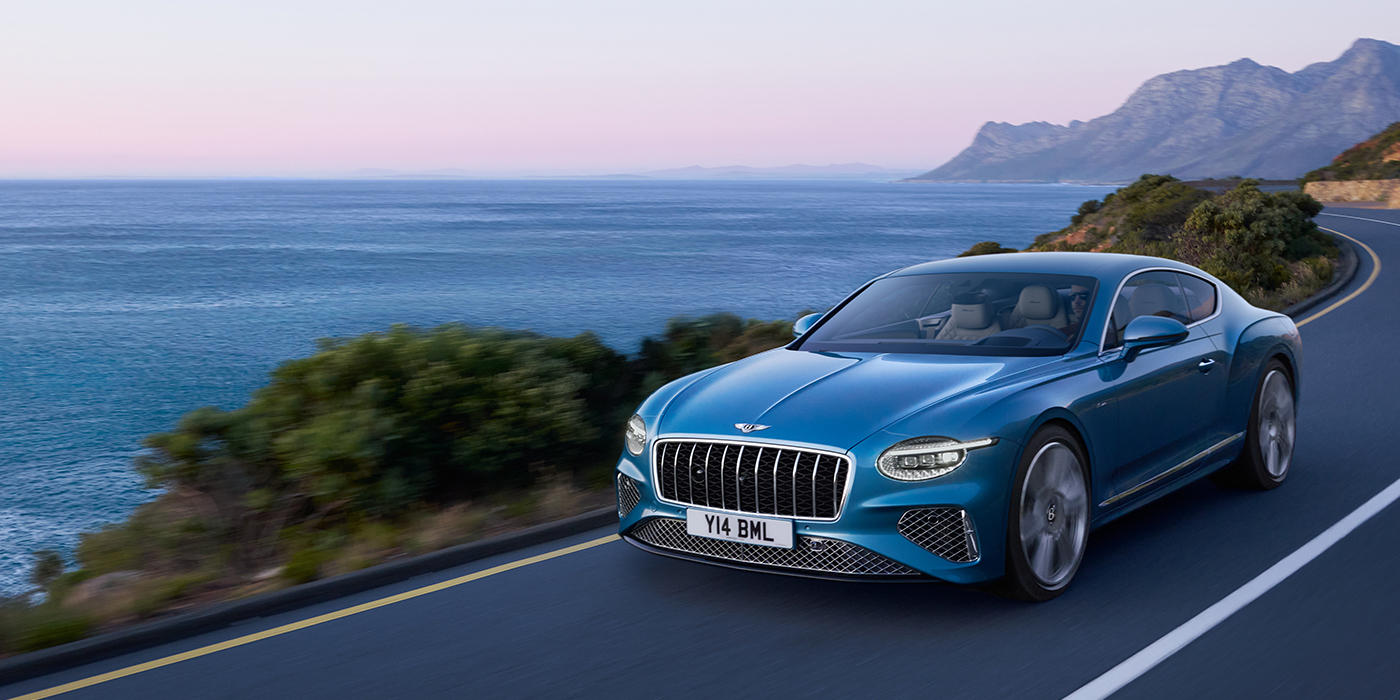 Bentley Roma New Bentley Continental GT Azure coupe in Light Windsor blue paint with 22 inch Azure wheels and chrome grill, driving dynamically by the sea