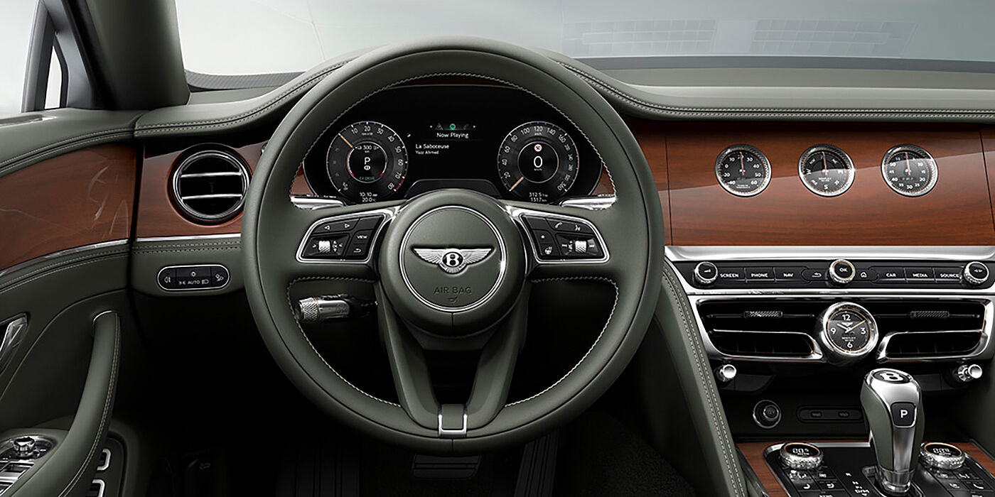 Bentley Roma New Bentley Flying Spur sedan front cabin in Cumbrian Green hide and Crown Cut walnut veneer showing steering wheel and Rotating Display with three clocks on face