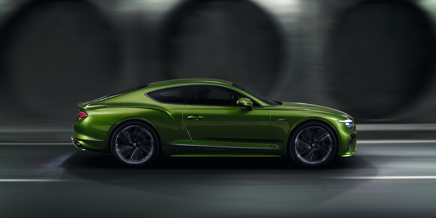 Bentley Roma Bentley Continental GT coupe in Tourmaline Green paint driving in profile on a dark road